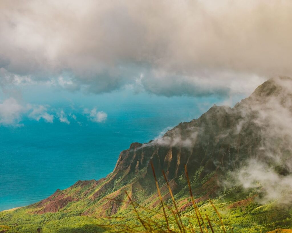 Cloud-covered coastal ridge rising above bright turquoise ocean
