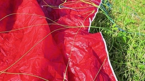 Close-up of wrinkled red ripstop fabric beside grass and cords