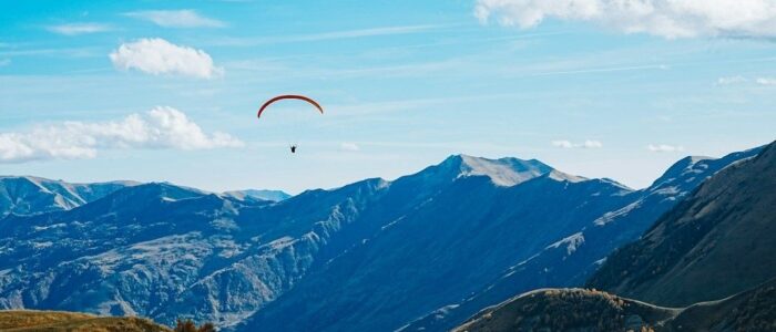 Paraglider soaring above a broad Alpine mountain valley
