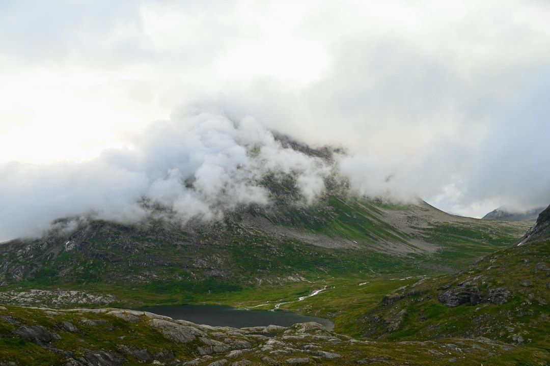 Cloud-wrapped alpine slopes above a small mountain lake and valley
